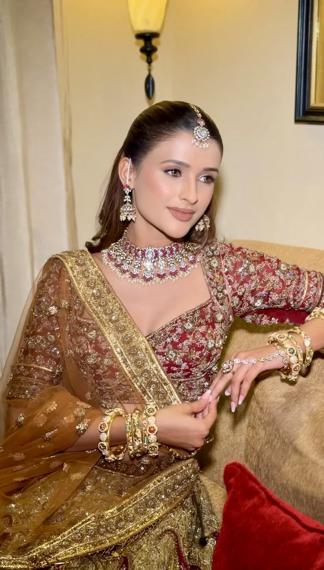 Bride seated in an olive and gold lehenga with layered diamond jewellery